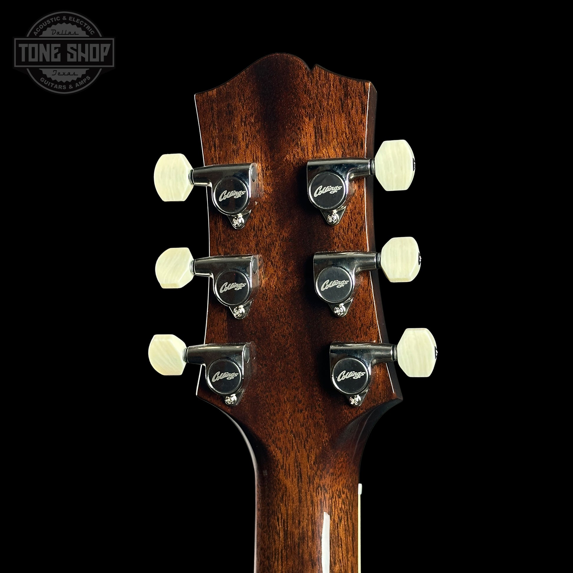 Close-up of a guitar headstock with tuning pegs on a black background, featuring the Tone Shop logo.
