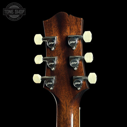 Close-up of a guitar headstock with tuning pegs on a black background, featuring the Tone Shop logo.