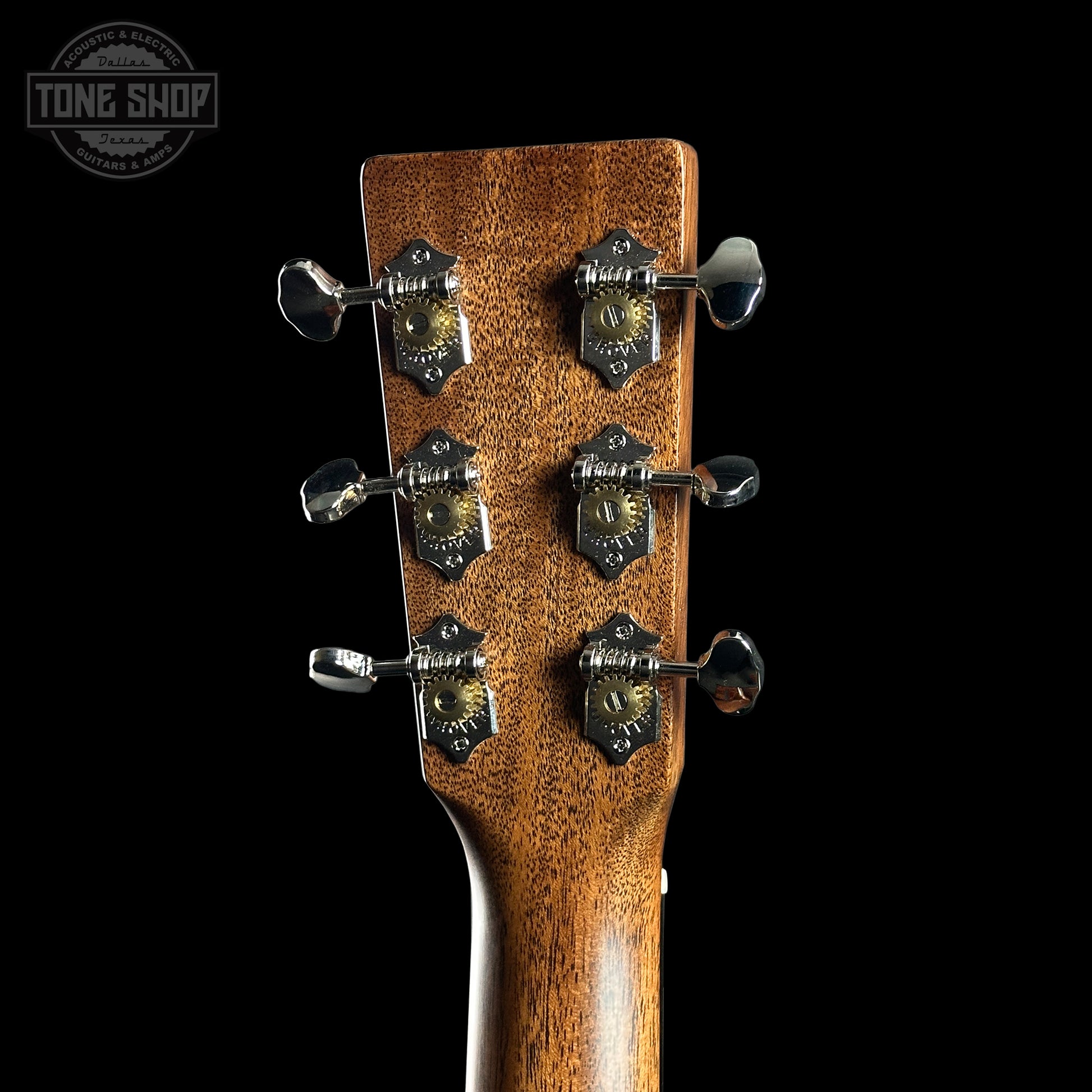 Close-up of a guitar headstock with tuning pegs on a black background, featuring the Tone Shop logo.