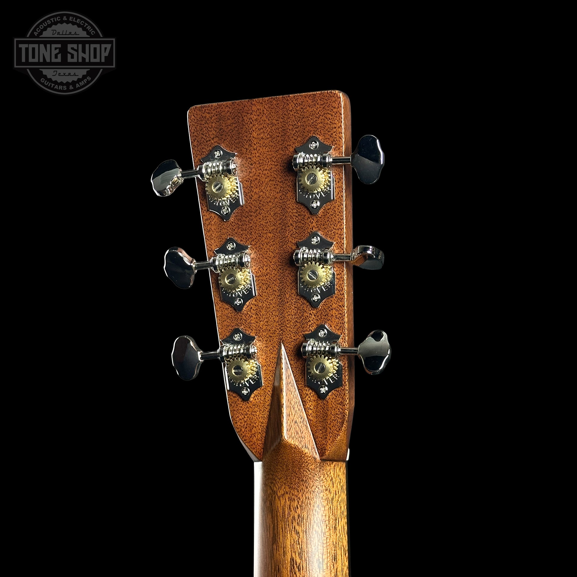 Close-up of a guitar headstock with tuning pegs on a black background, featuring the Tone Shop logo.