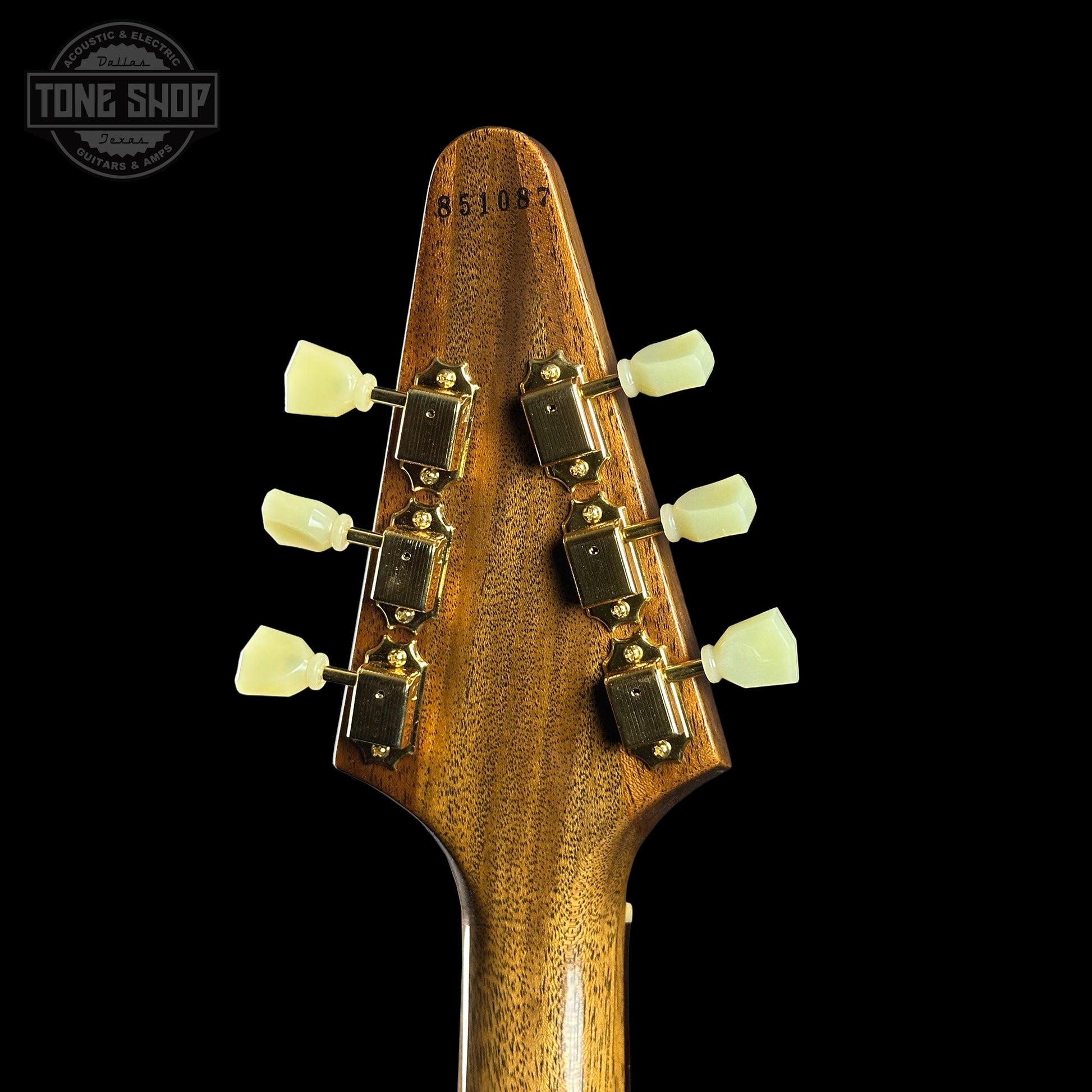 Close-up of a guitar headstock with tuning pegs on a black background, featuring the Tone Shop logo.
