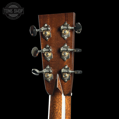 Close-up of a guitar headstock with tuning pegs on a black background, featuring the Tone Shop logo.