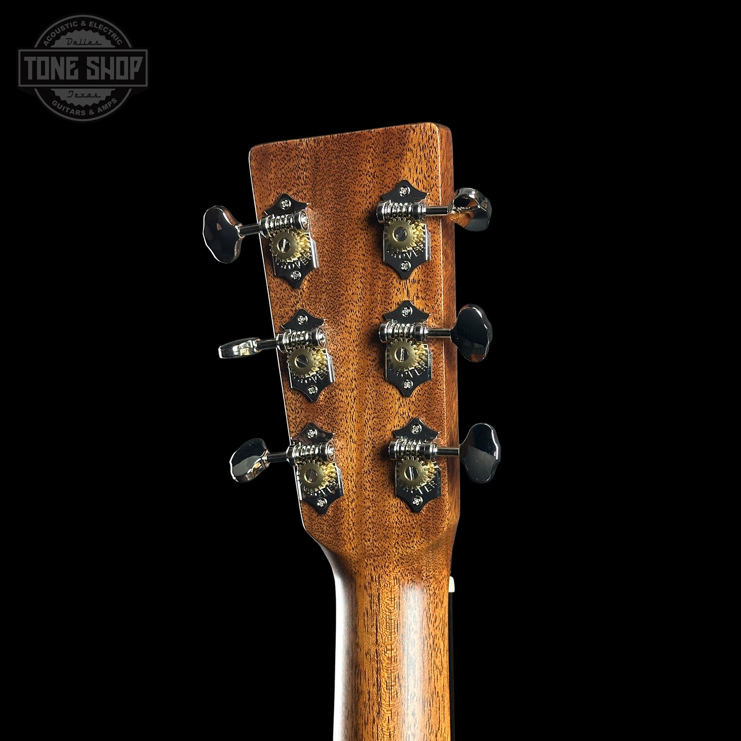 Close-up of a guitar headstock with tuning pegs on a black background, featuring the Tone Shop logo.