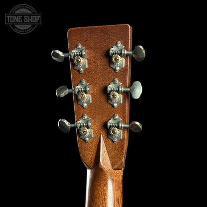 Close-up of a guitar headstock with tuning pegs on a black background, featuring the Tone Shop logo.