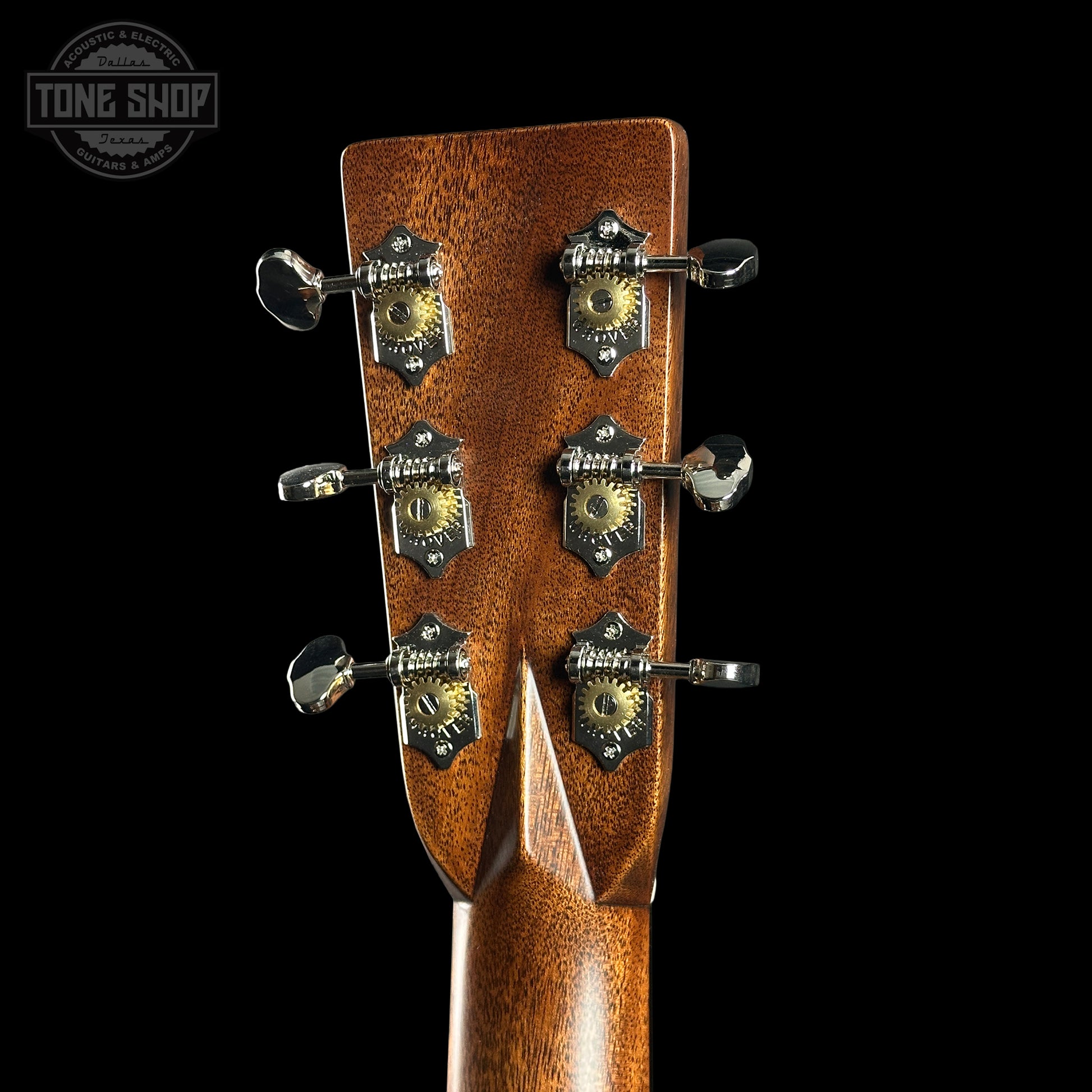 Close-up of a guitar headstock with tuning pegs on a black background, featuring the Tone Shop logo.