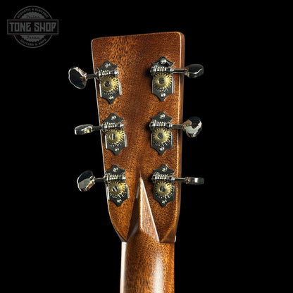 Close-up of a guitar headstock with tuning pegs on a black background, featuring the Tone Shop logo.