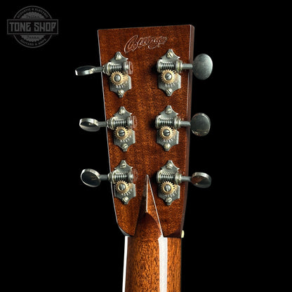 Close-up of a guitar headstock with tuning pegs on a black background, featuring the 'Tone Shop' logo.