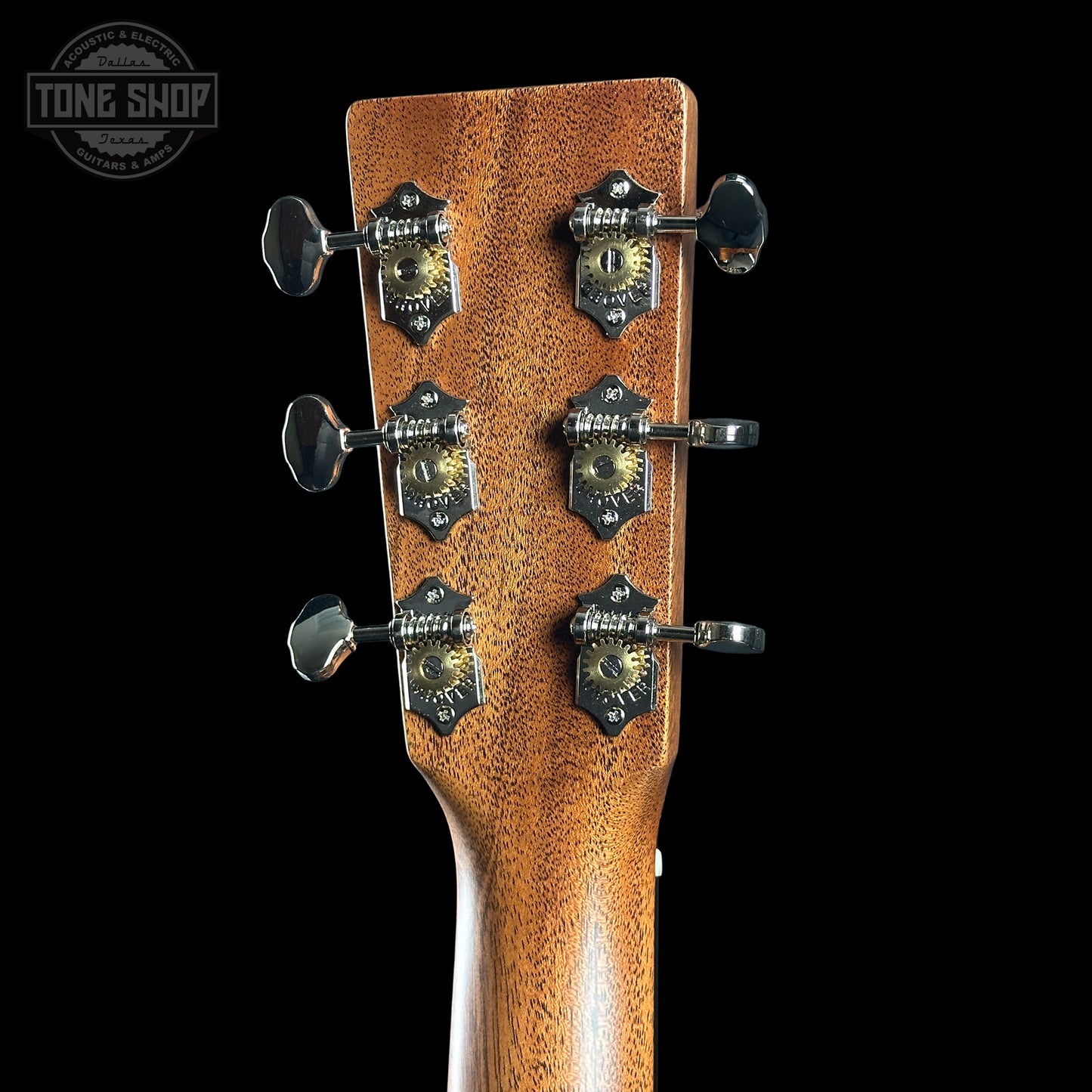 Close-up of a guitar headstock with tuning pegs on a black background, featuring the Tone Shop logo.