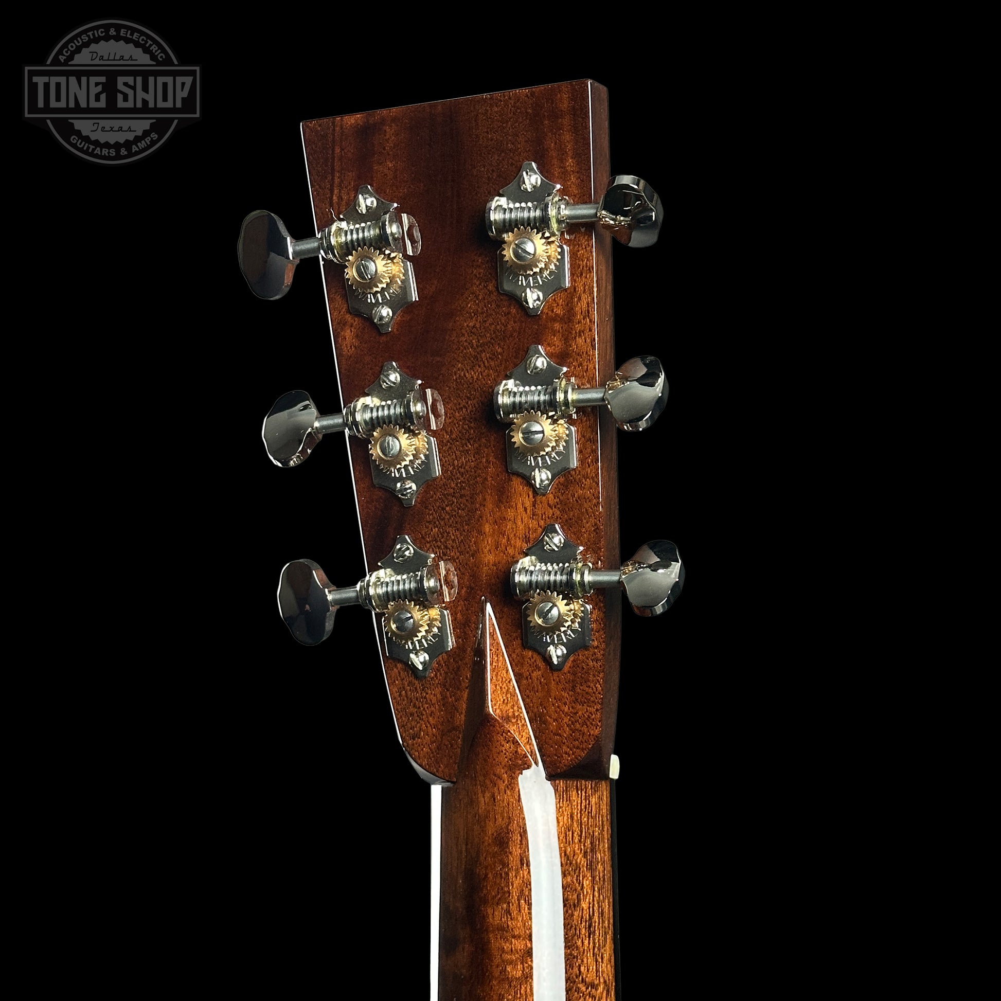 Close-up of a guitar headstock with tuning pegs on a black background, featuring the Tone Shop logo.