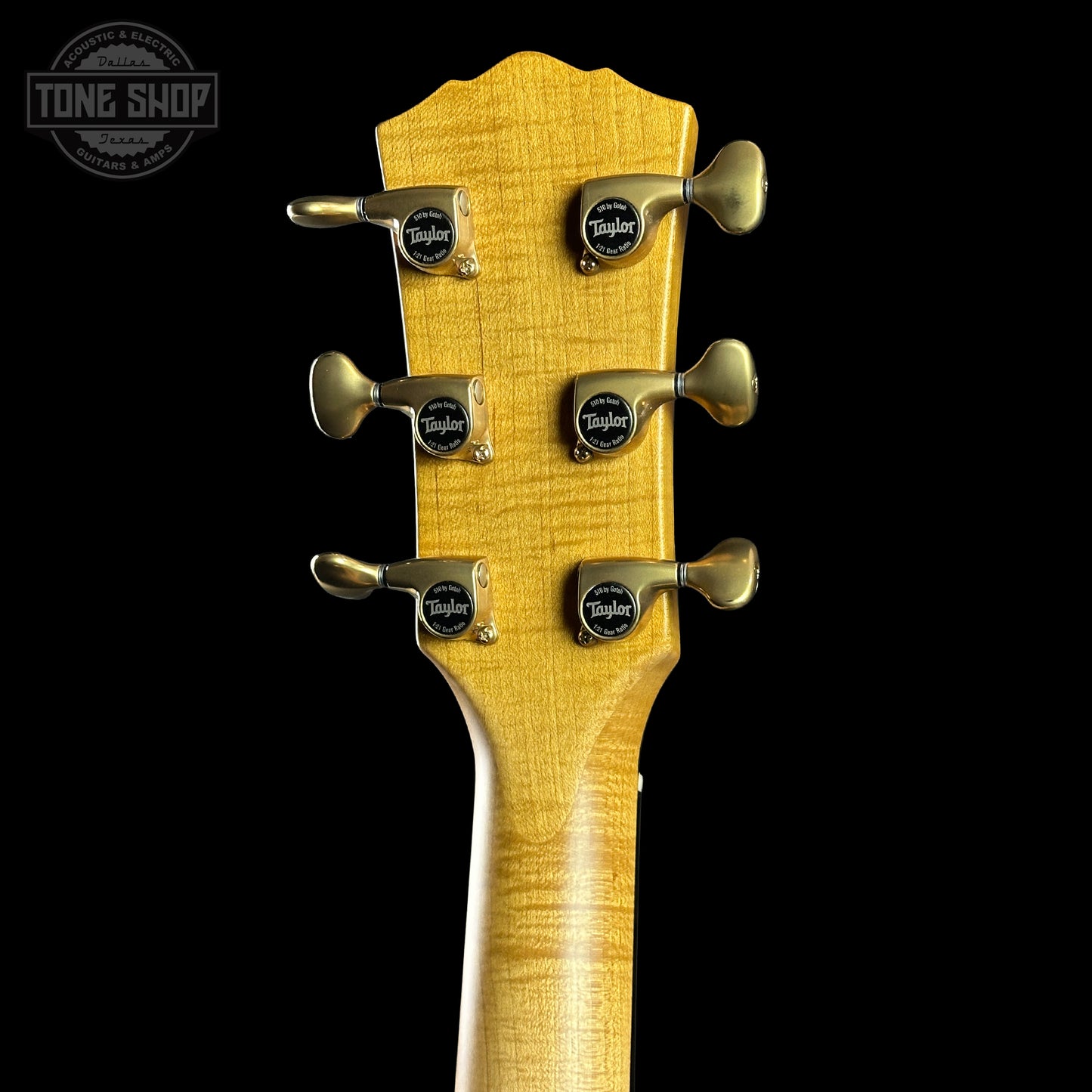 Guitar headstock with tuning pegs on a black background, featuring the Taylor logo.