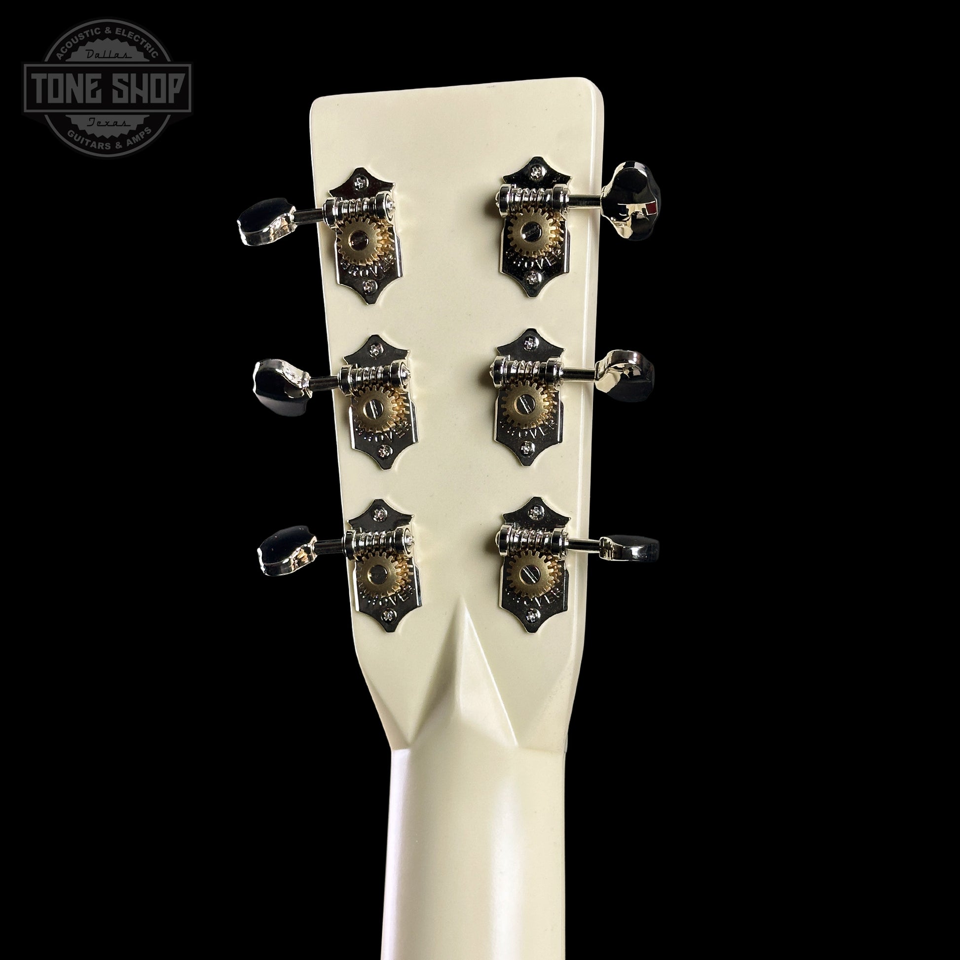 Close-up of a guitar headstock with tuning pegs on a black background, featuring the Tone Shop logo.