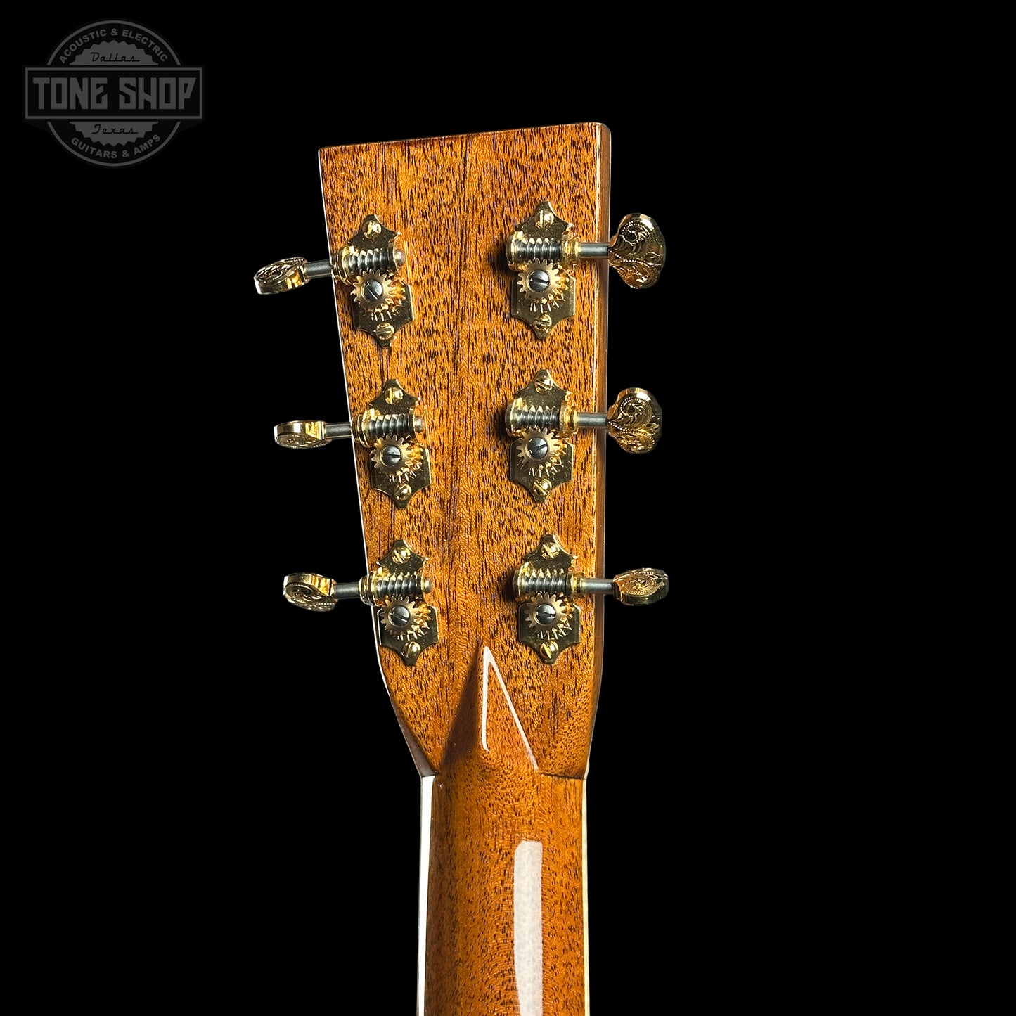 Close-up of a guitar headstock with tuning pegs on a black background, featuring the Tone Shop logo.