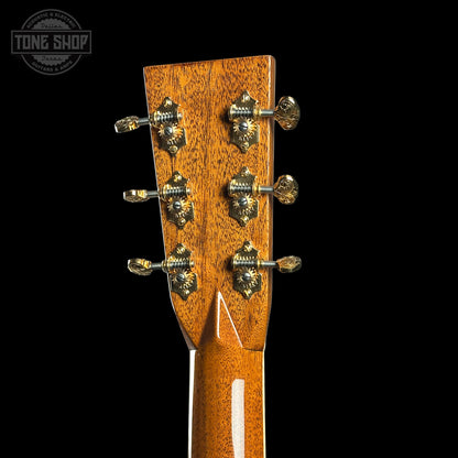Close-up of a guitar headstock with tuning pegs on a black background, featuring the Tone Shop logo.