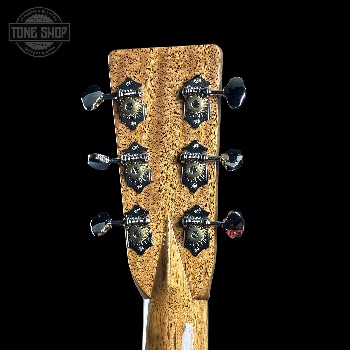 Close-up of a guitar headstock with tuning pegs on a black background, featuring the Tone Shop logo.