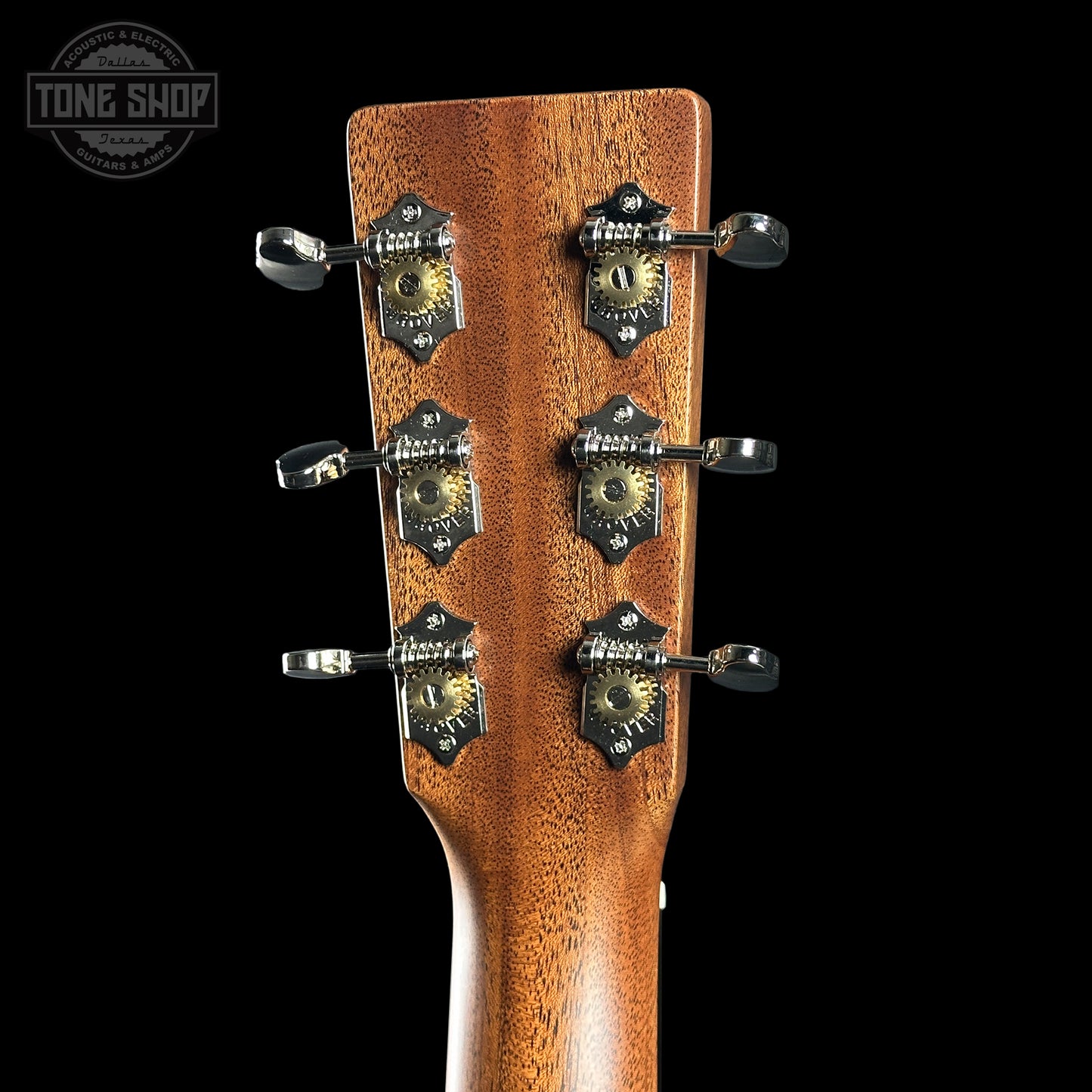 Close-up of a guitar headstock with tuning pegs on a black background, featuring the Tone Shop logo.