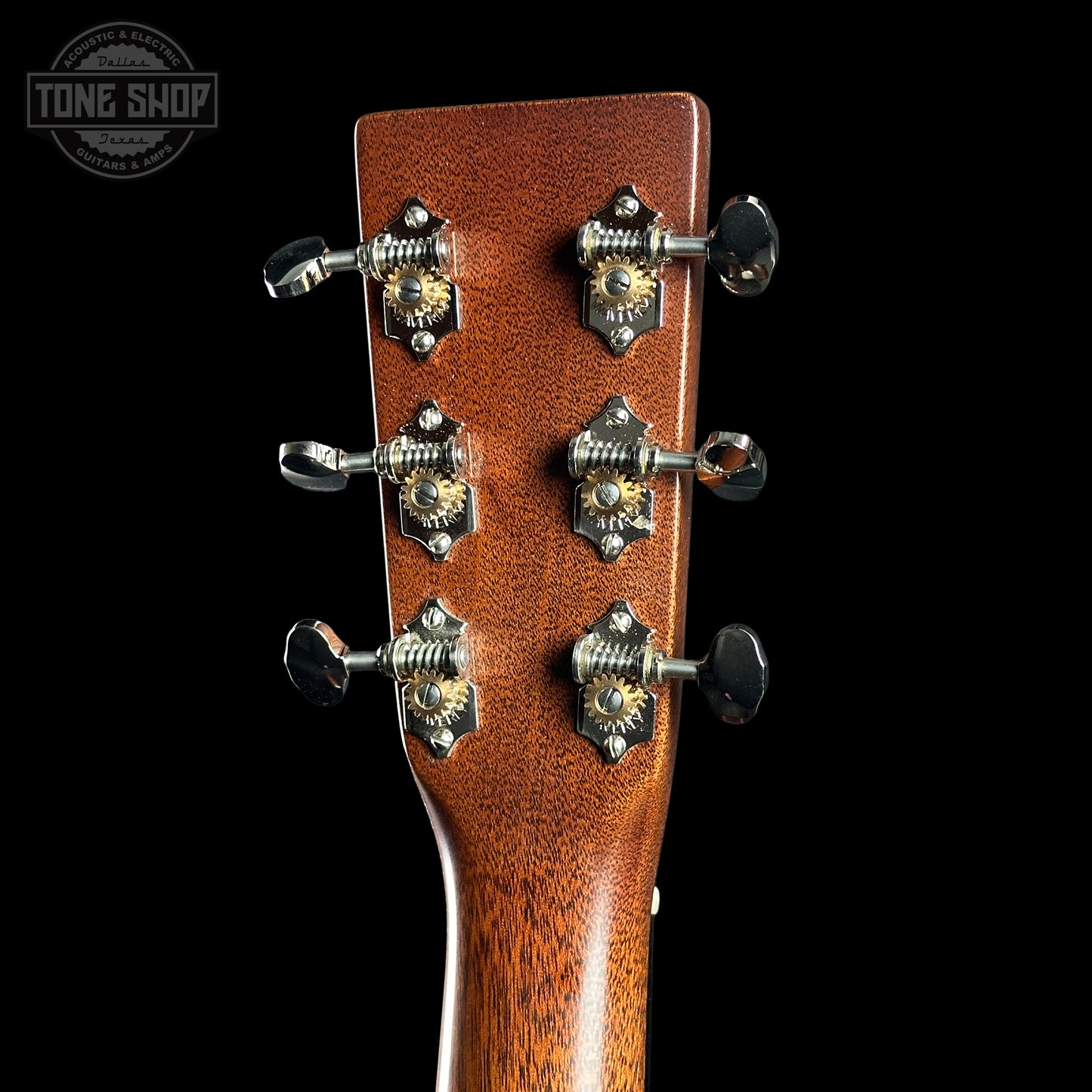 Close-up of a guitar headstock with tuning pegs on a black background, featuring 'Tone Shop' branding.