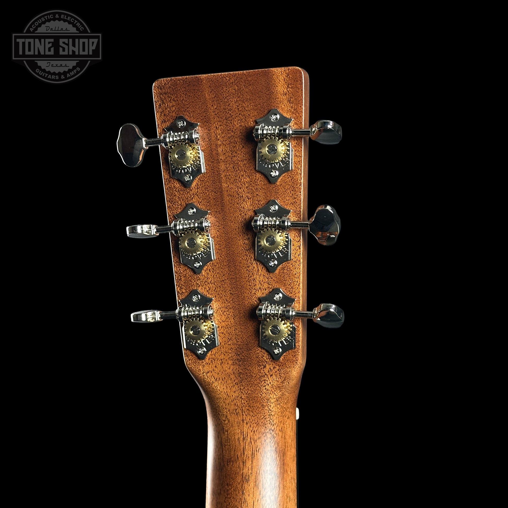 Close-up of a guitar headstock with tuning pegs on a black background, featuring the Tone Shop logo.