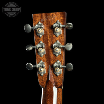 Close-up of a guitar headstock with tuning pegs on a black background, featuring the Tone Shop logo.