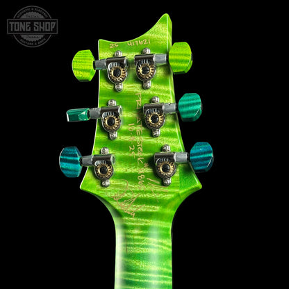 Close-up of a green guitar headstock with tuning pegs on a black background, featuring 'Tone Shop' branding.