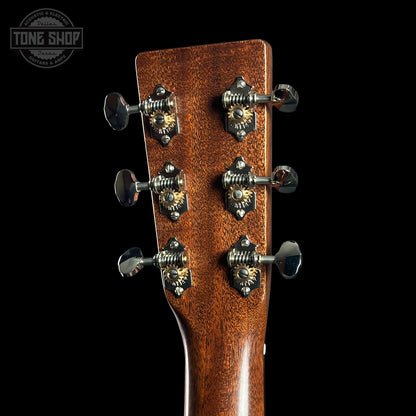 Close-up of a guitar headstock with tuning pegs on a black background, featuring the Tone Shop logo.