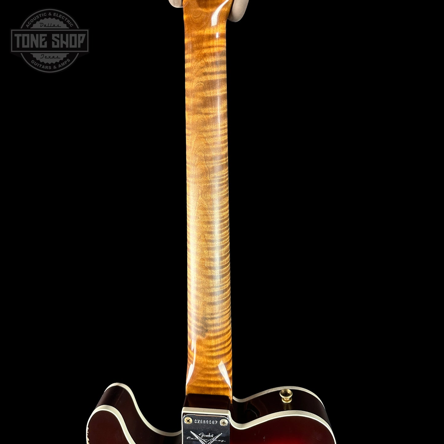 Close-up of a guitar neck with a dark background, featuring the 'Tone Shop' logo.