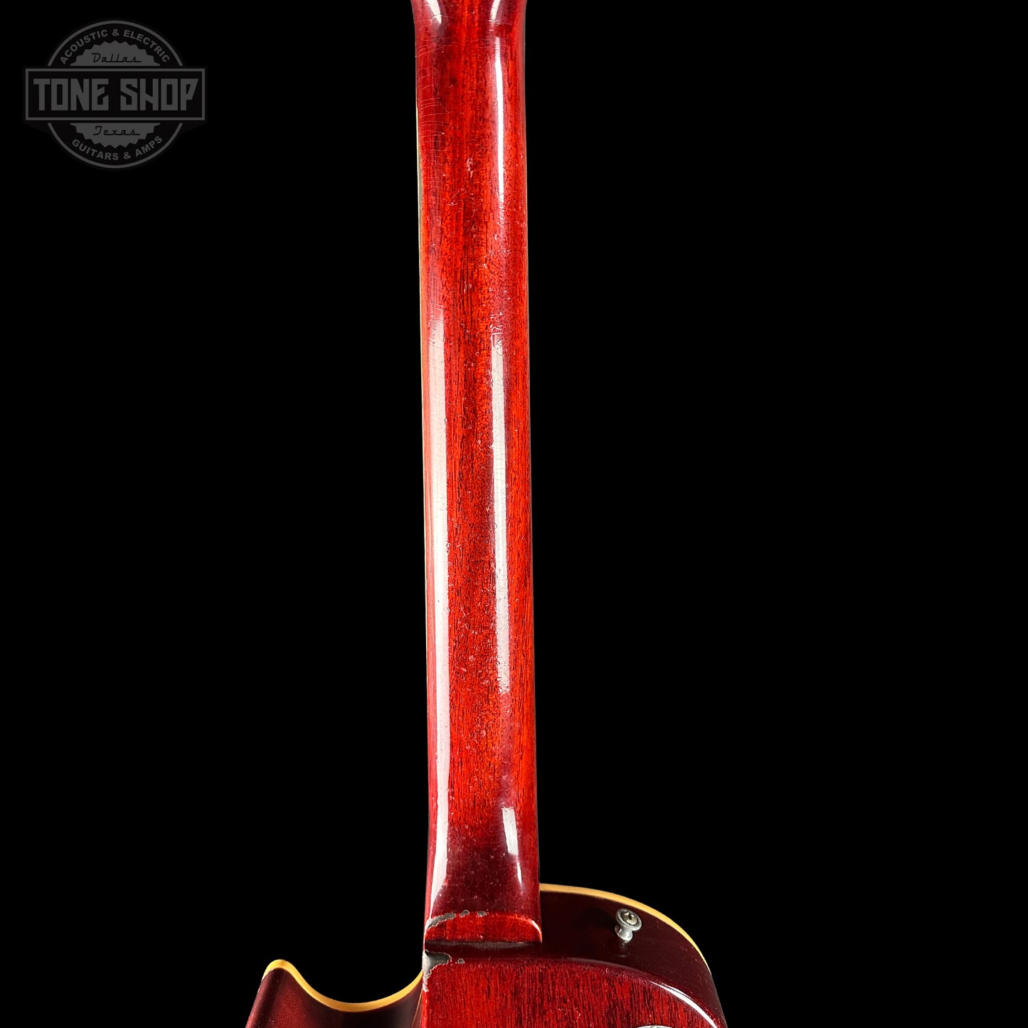 Close-up of a red guitar neck with 'Tone Shop' logo in the corner.