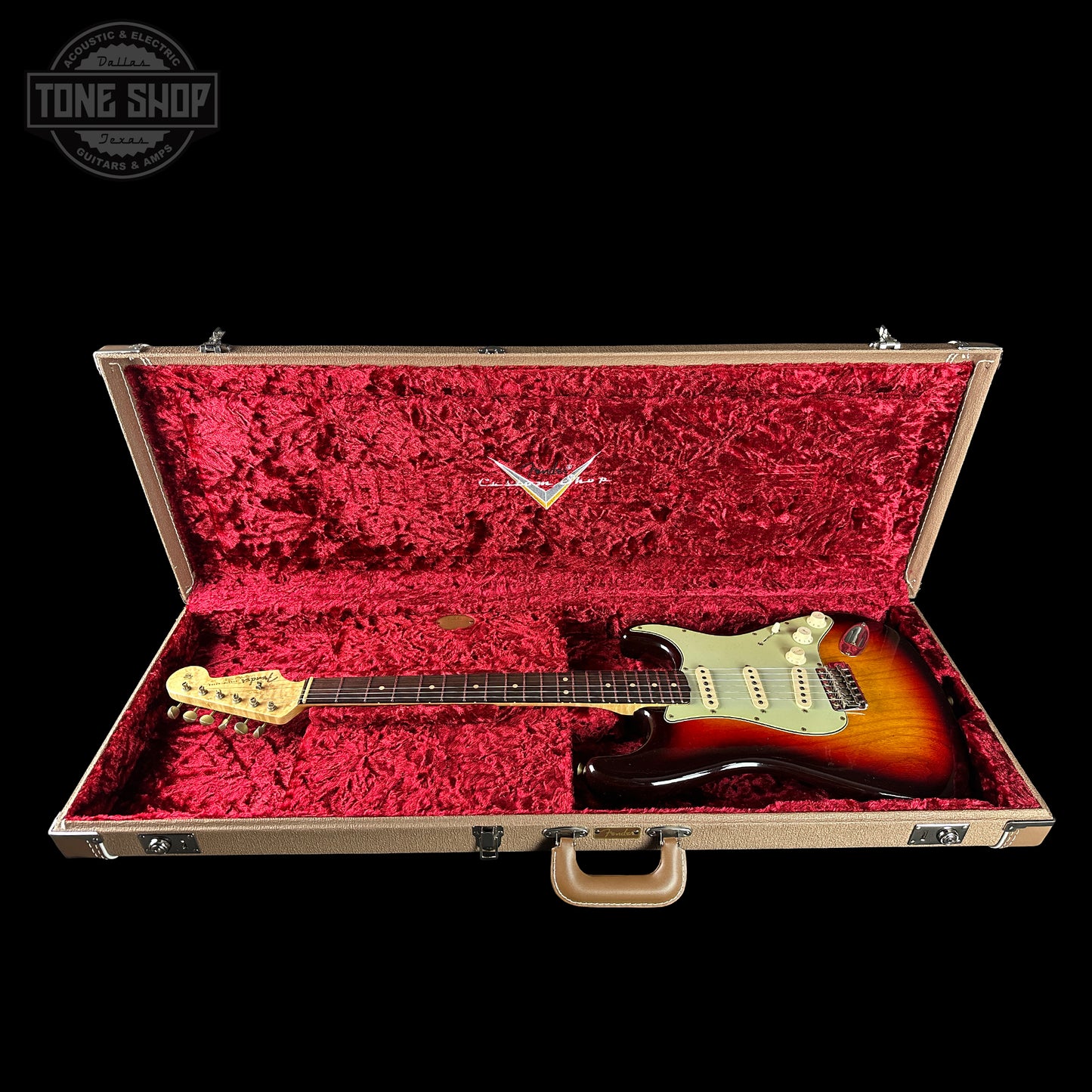 Fender Stratocaster guitar in a red-lined case with 'Tone Shop' logo.