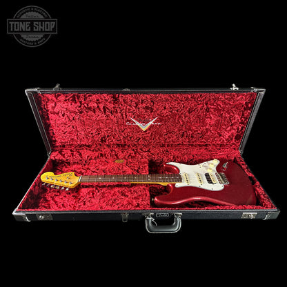 Red electric guitar in an open black case with red interior