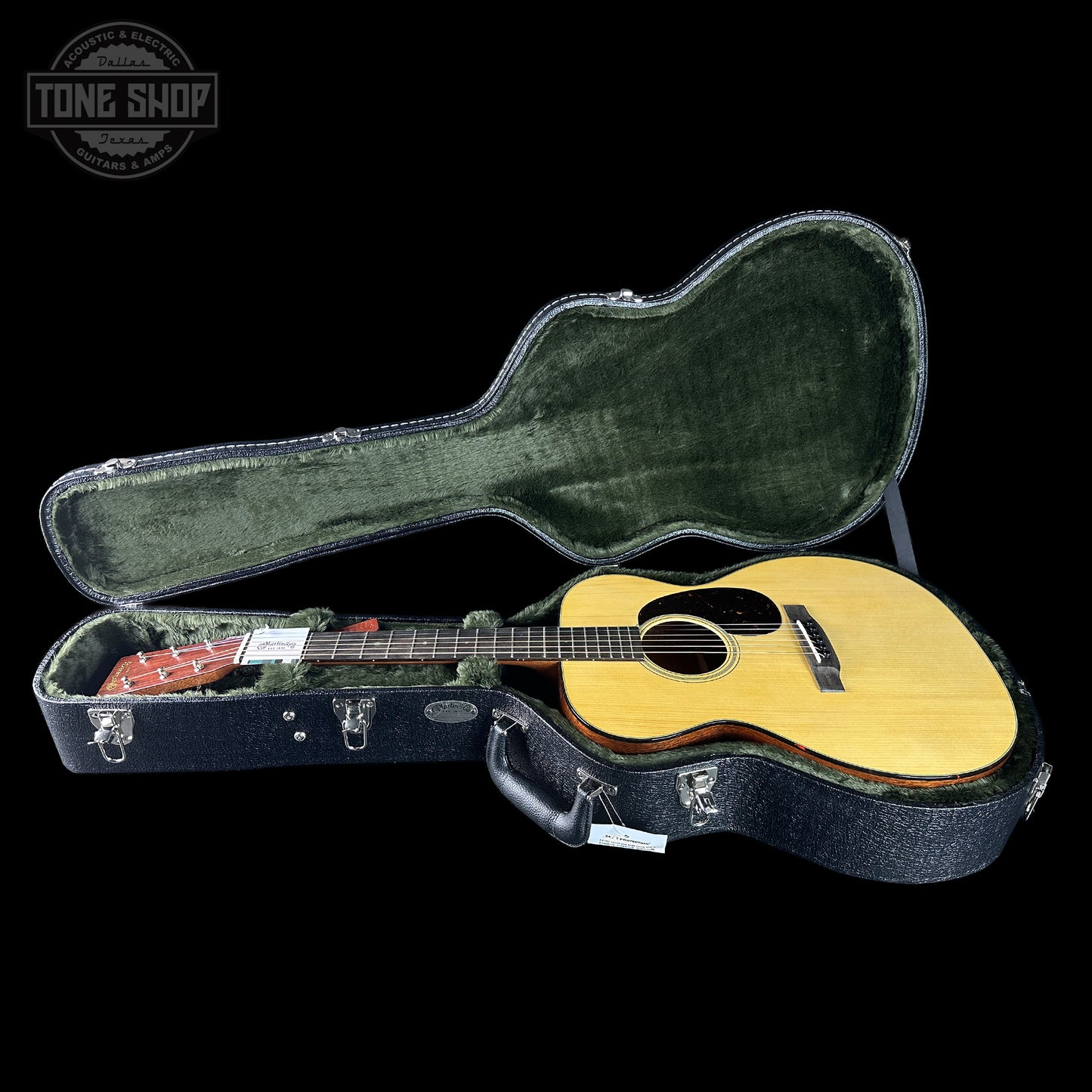 Acoustic guitar in a hard-shell case with 'Tone Shop' logo in the corner.