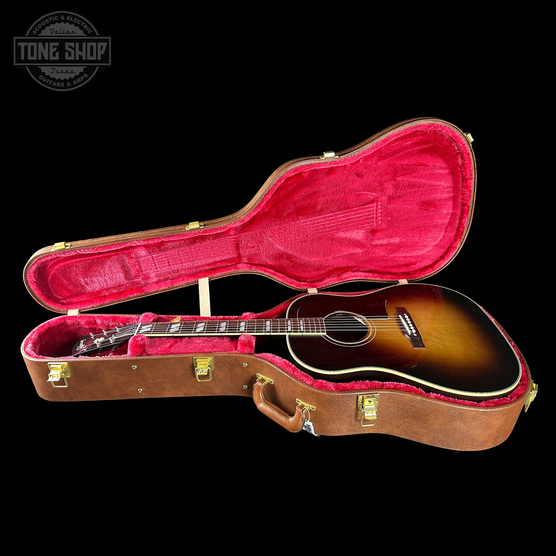 Acoustic guitar in a brown case with red interior on a black background, featuring 'Tone Shop' logo.