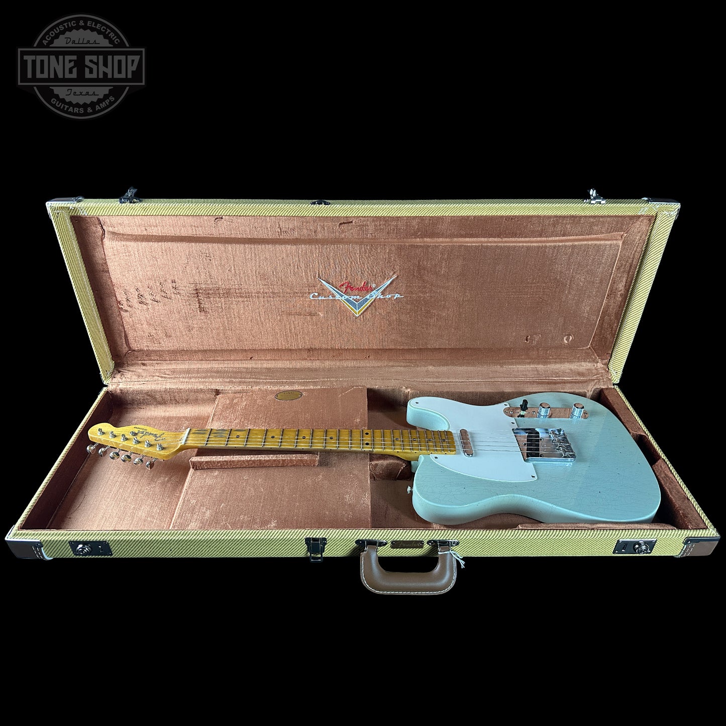 Light blue electric guitar in an open case with a visible brand logo on a black background.