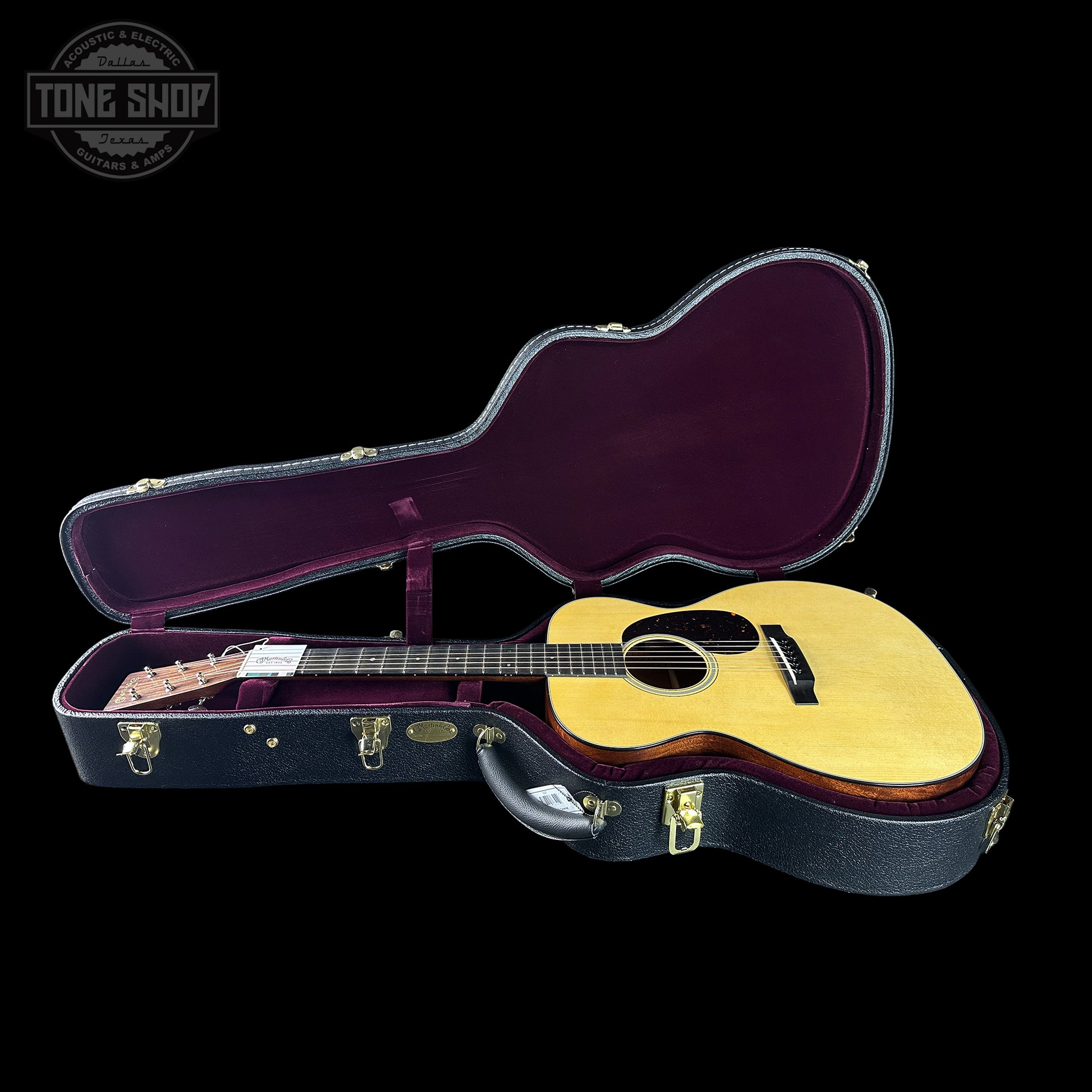 Acoustic guitar in an open case with 'Tone Shop' logo in the corner.