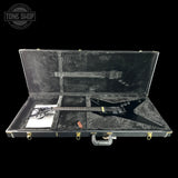 Black electric guitar in a hard-shell case with 'Tone Shop' logo.