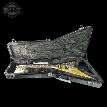 Gold electric guitar in a black case with 'Tone Shop' logo.