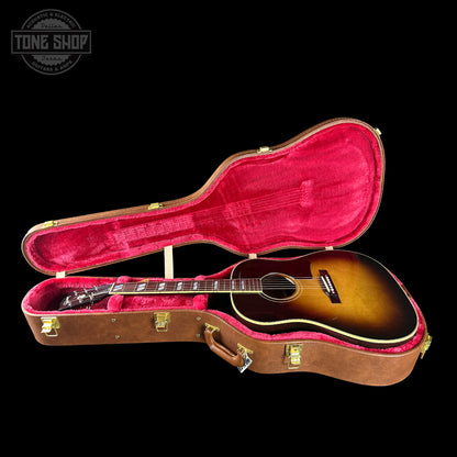 Guitar in an open case with a visible brand logo on a black background