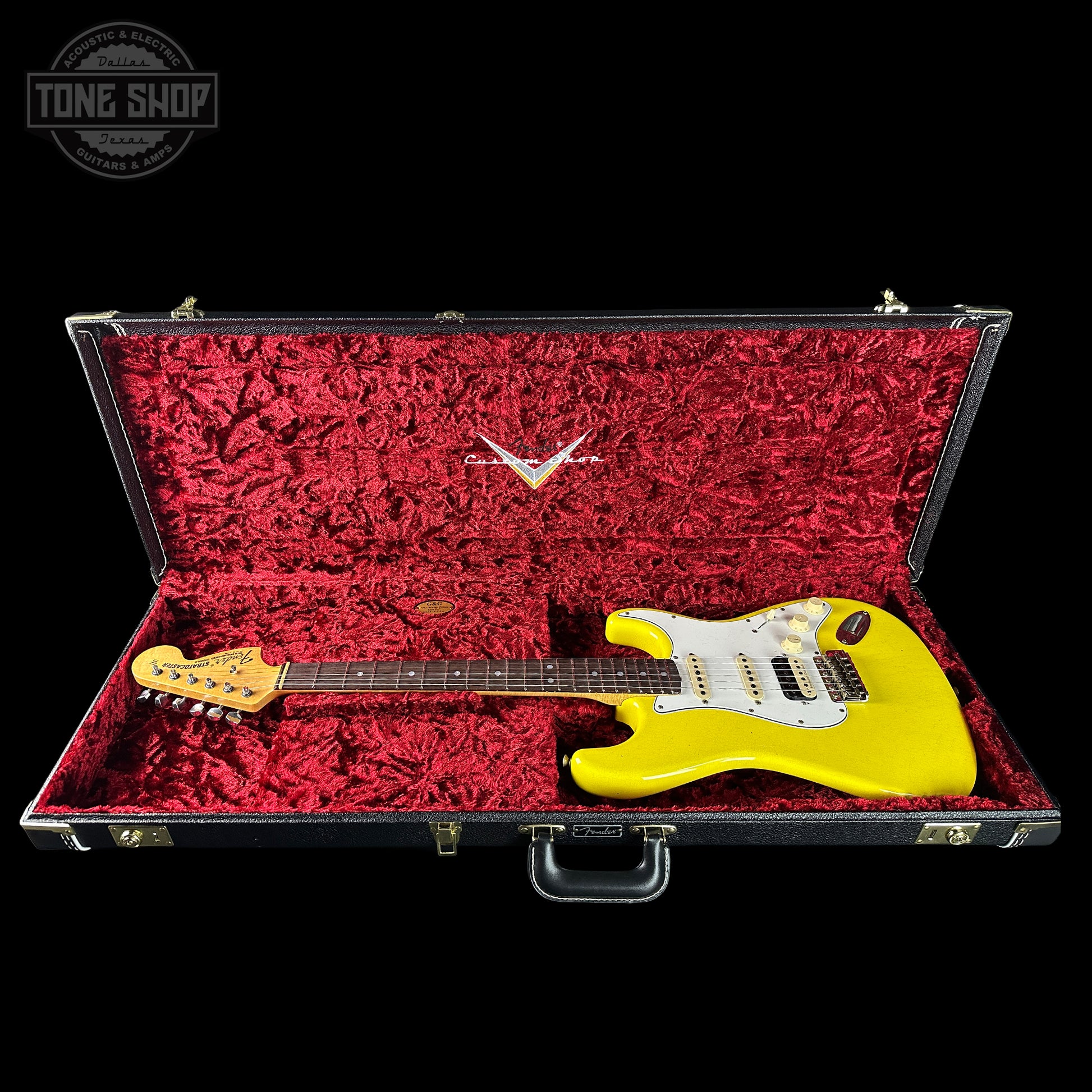 Yellow electric guitar in a red-lined case with 'Tone Shop' logo.