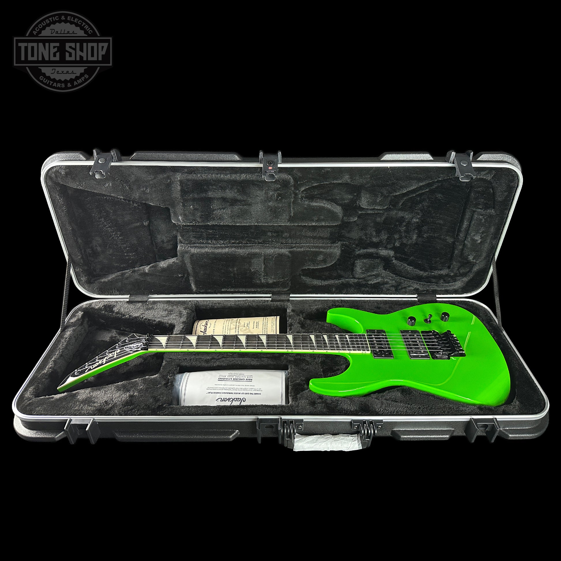 Green electric guitar in a case with 'Tone Shop' branding.