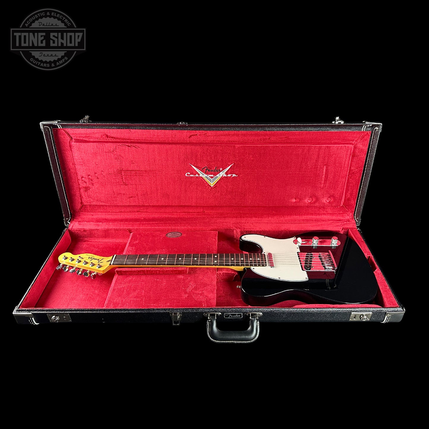 Guitar in a red-lined case with a visible brand logo on a black background