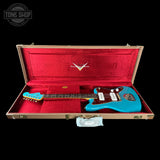 Blue electric guitar in a red-lined case with a visible brand logo on a black background.
