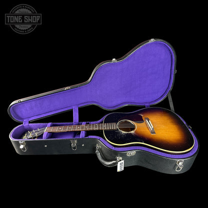 Acoustic guitar in a black and purple case with 'Tone Shop' logo.