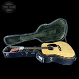 Acoustic guitar in a hard-shell case with 'Tone Shop' logo in the corner.