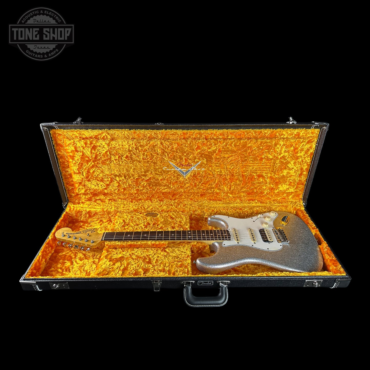 Silver electric guitar in a black case with gold interior, brand 'Tone Shop' visible.