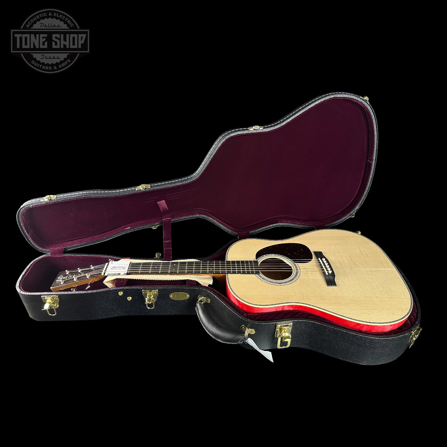 Acoustic guitar in an open case with 'Tone Shop' logo in the corner.