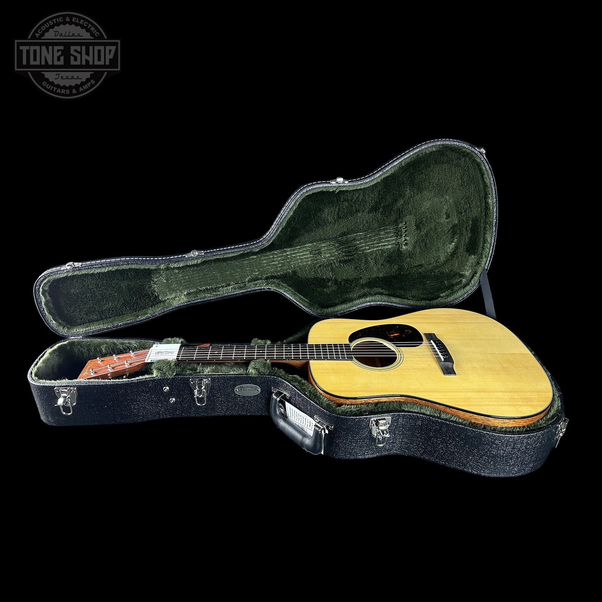 Acoustic guitar in a hard-shell case on a black background with 'Tone Shop' logo.