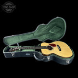 Acoustic guitar in a green case with 'Tone Shop' logo in the corner.