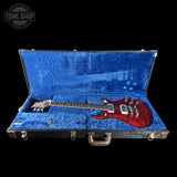 Red electric guitar in a blue case with 'Tone Shop' logo.