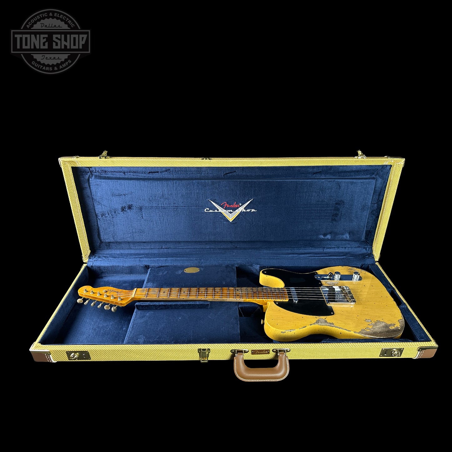 Yellow electric guitar in a blue case with a visible brand logo on a black background.
