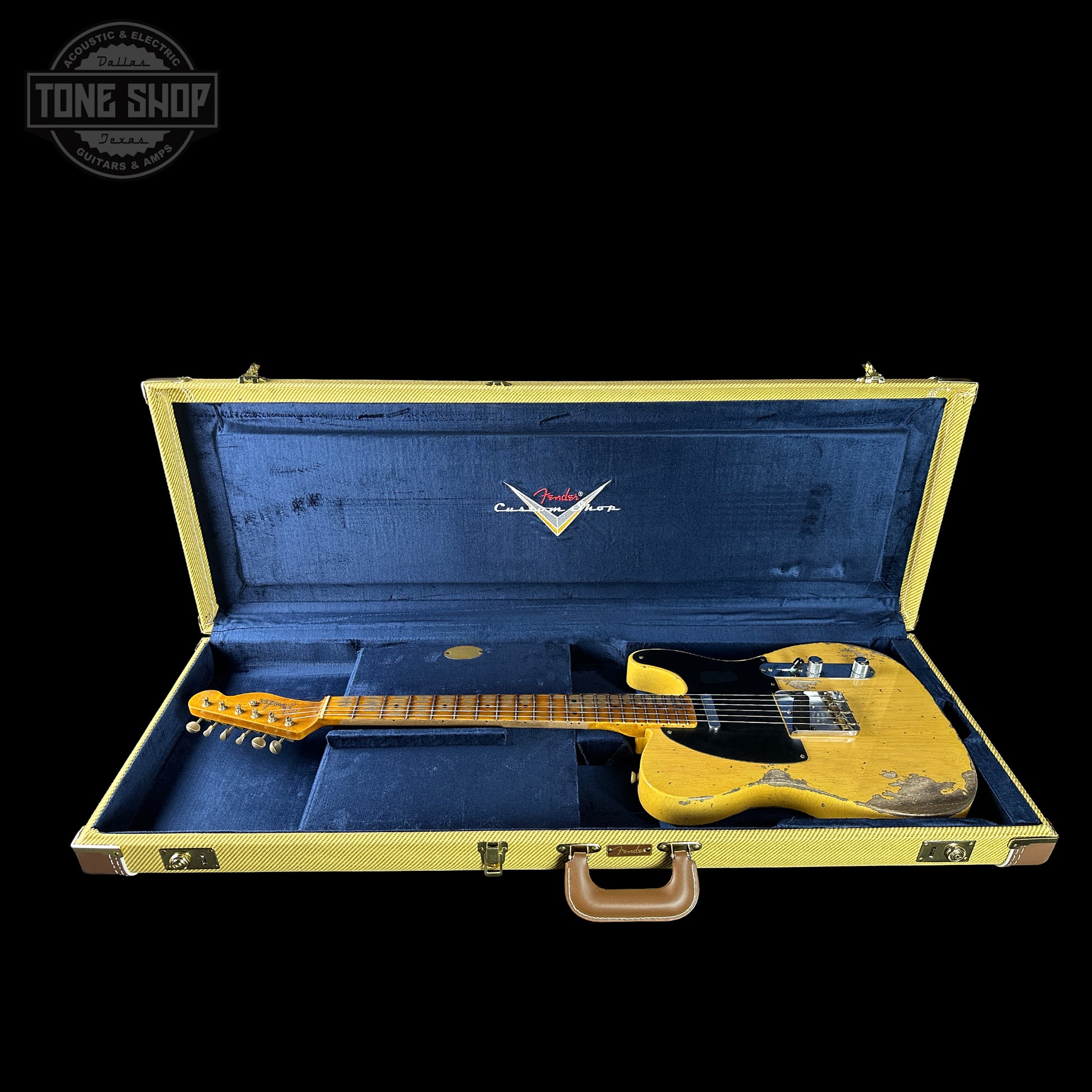 Yellow electric guitar in a blue case with a visible brand logo on a black background.
