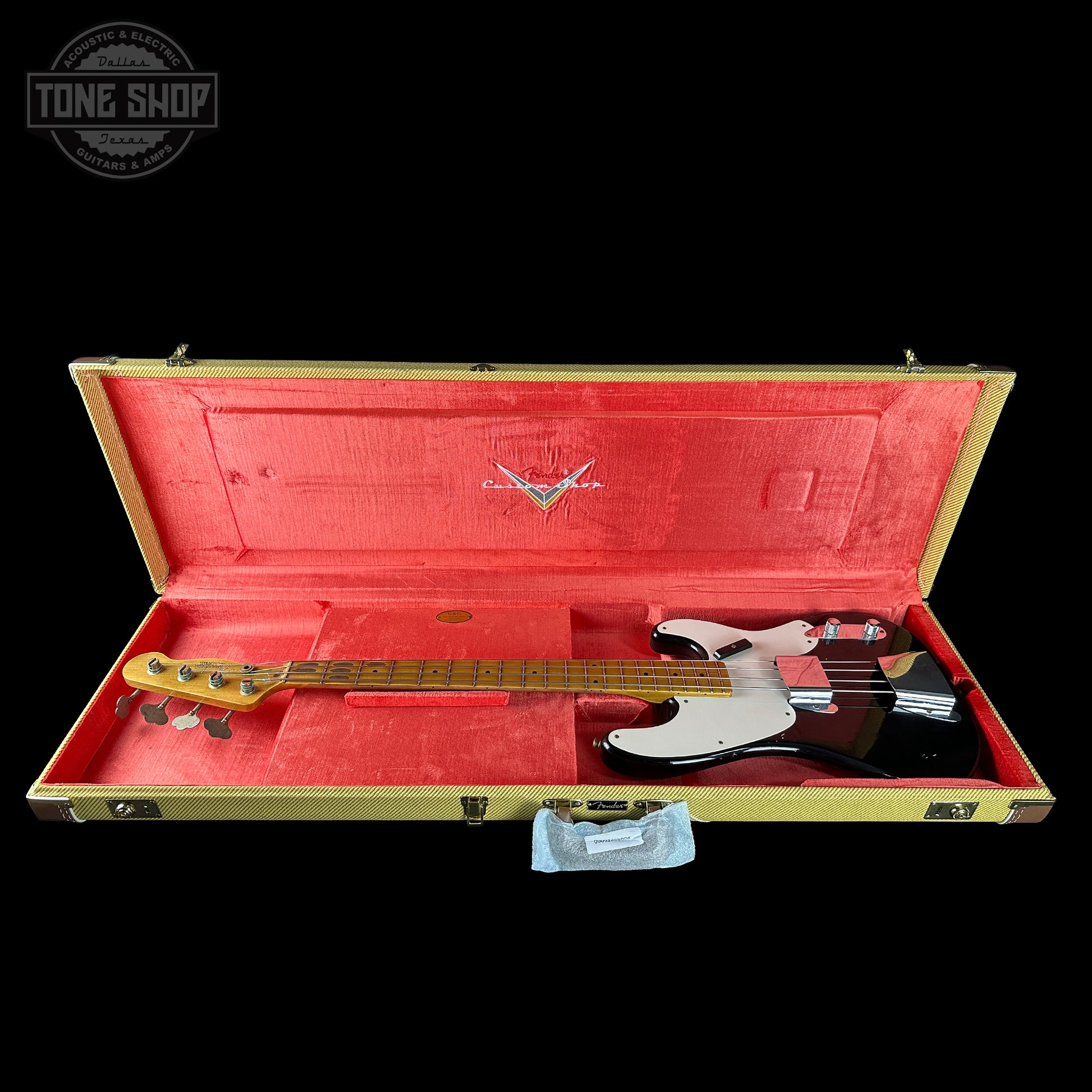 Electric bass guitar in a red-lined case with a visible brand logo on a black background.