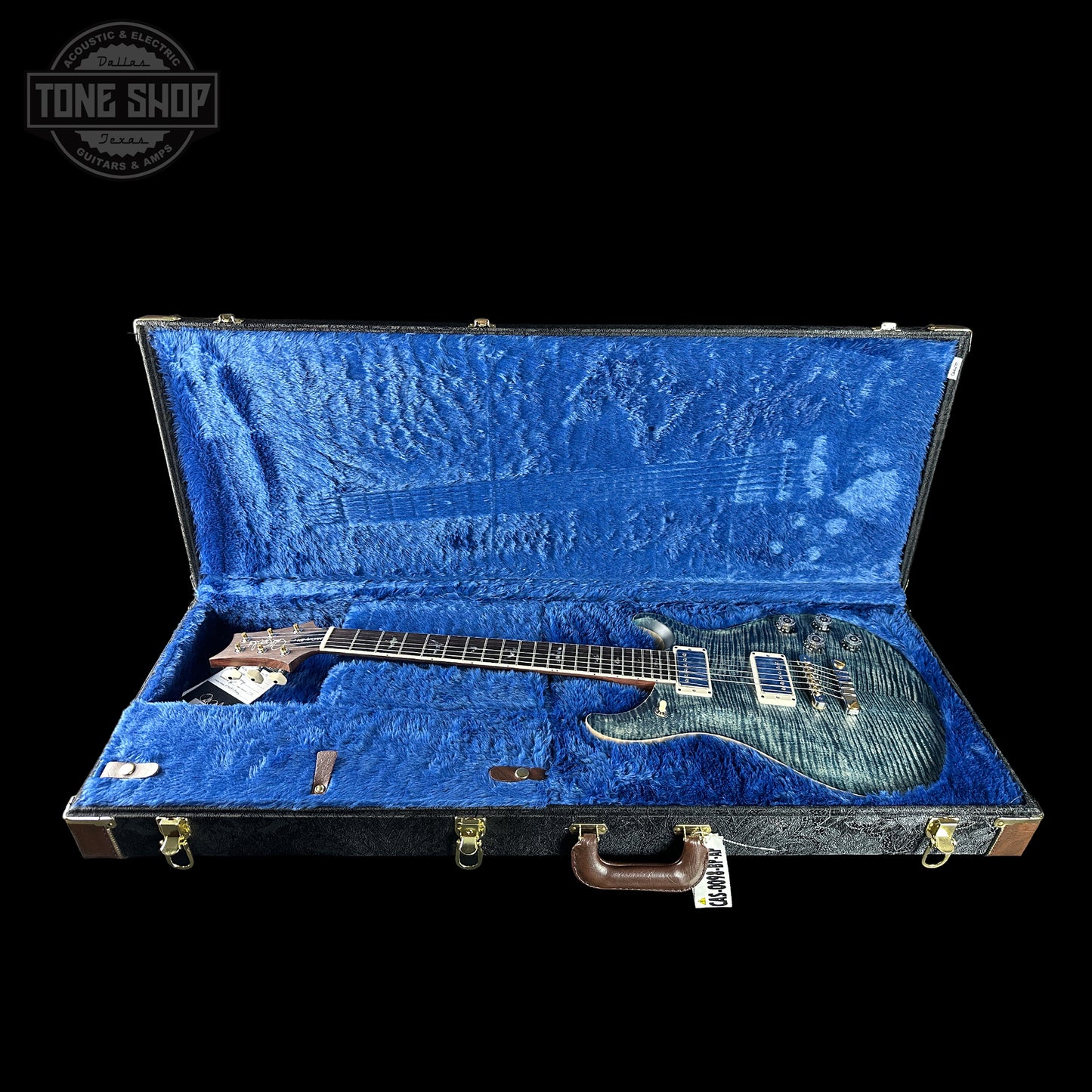 Guitar in an open blue case with 'Tone Shop' logo.